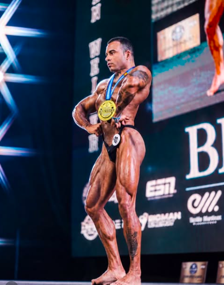 Lucas Almeida posando em forma de competição no palco